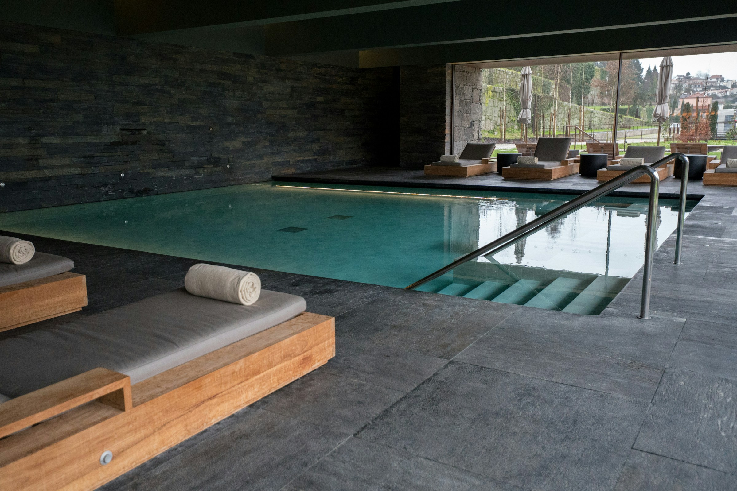 Dark stone indoor pool with loungers